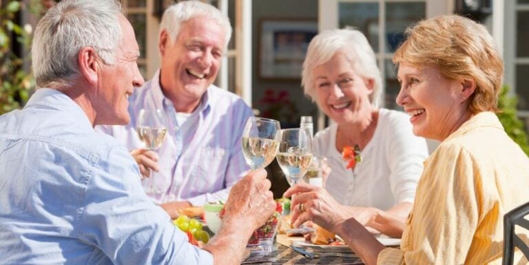 Elderly Friends Laughing and Toasting with Wine Outdoors at an Independent Living Facility
