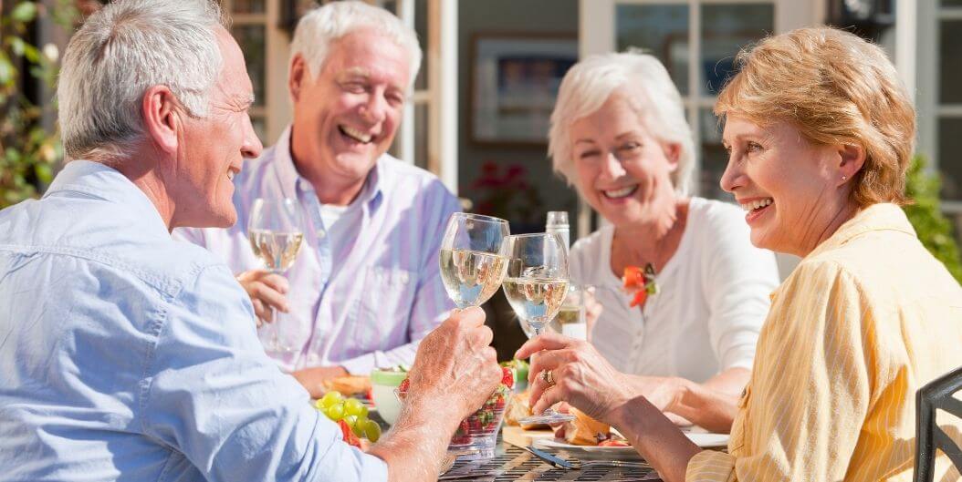 Elderly Friends Laughing and Toasting with Wine Outdoors at an Independent Living Facility