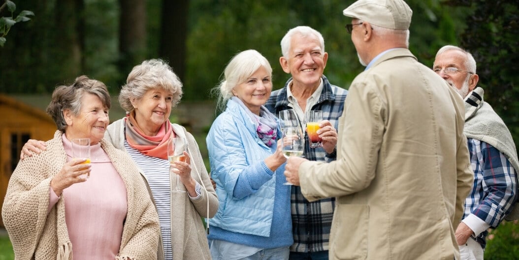 Group of Seniors Socializing Outdoors with Drinks at an Independent Living Facility
