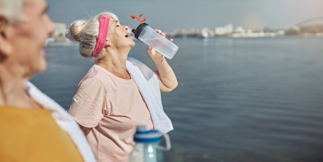 Elderly Woman Drinking Water Outdoors near Independent Living Facility