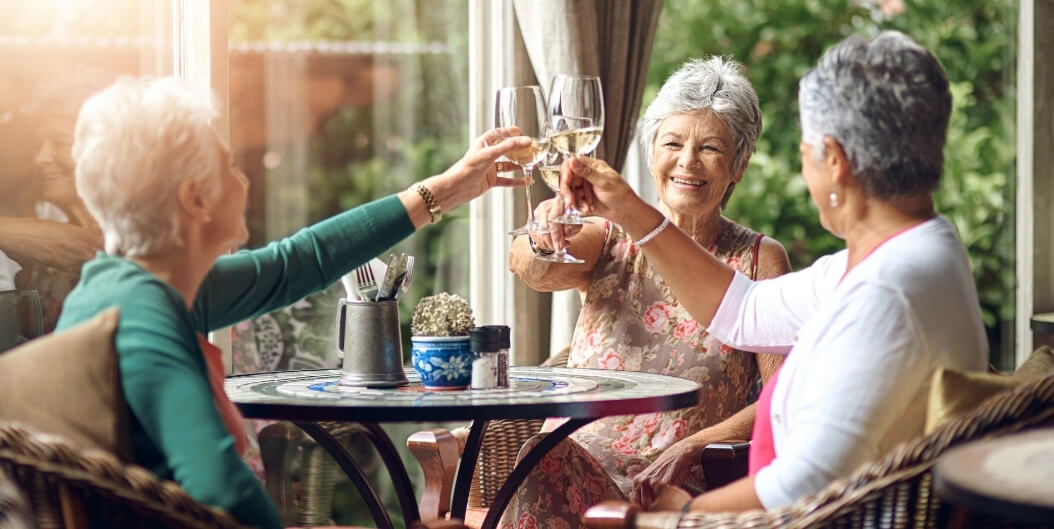 Elderly Women Toasting Together on Sunny Patio at Independent Facility